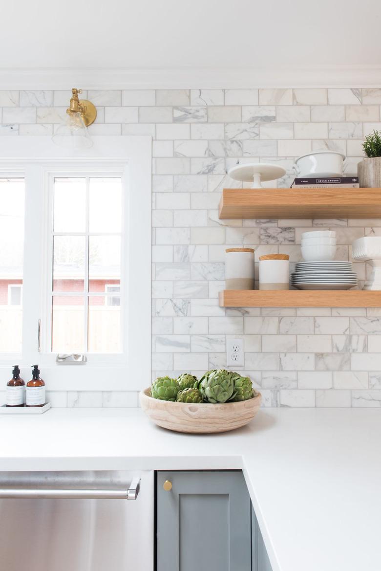 marble subway tile kitchen backsplash with open shelving and gray cabinets