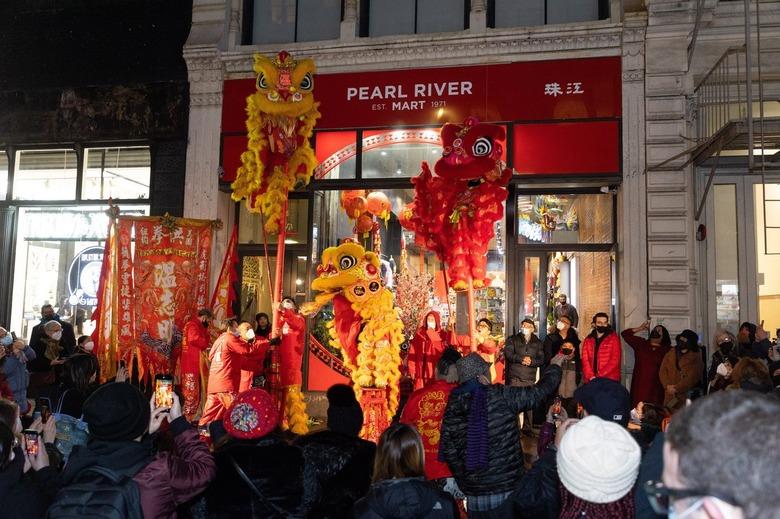 The Pearl River Mart storefront with lion dancers in front and a crowd of people on the street.