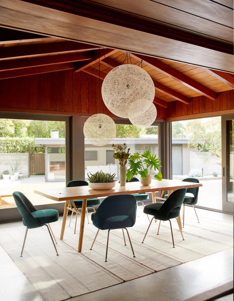 teal color chairs in midcentury modern dining room with wood ceiling