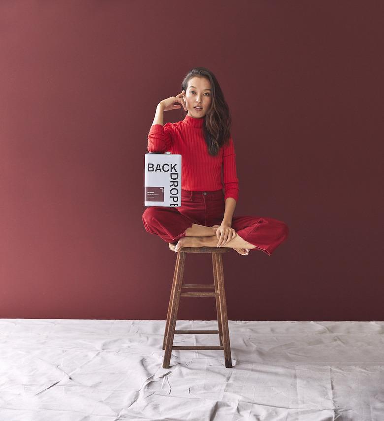 woman posing with paint near a dark red wall