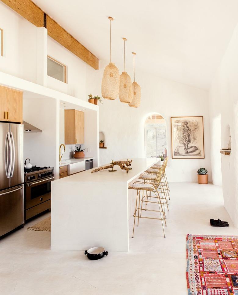 a long breakfast bar in a narrow, open kitchen with pendant lights