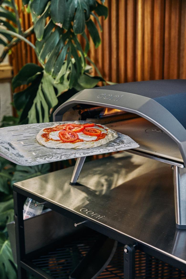 A person putting a pizza inside a small oven