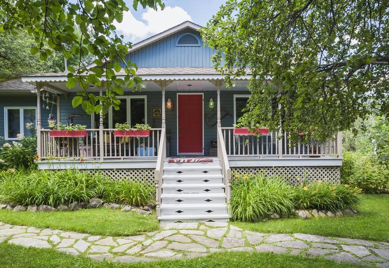 Country cottage style residential home facade with veranda in summer