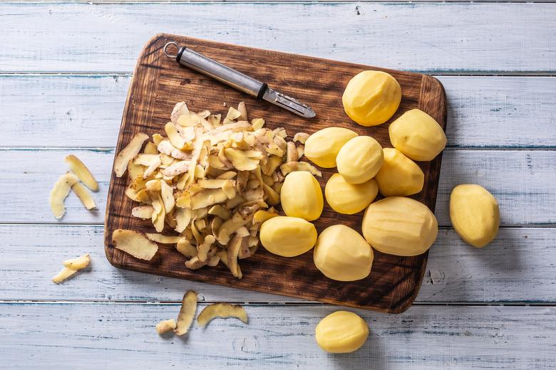 Peeled potatoes on a cutting board - top of view.