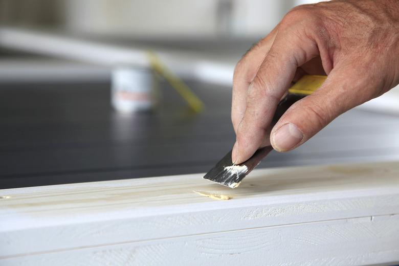 Preparation woodwork. Close-up details Putty knife in man's hand. DIY worker applying filler to the wood. Removing holes from a wood surface. Application of putty.