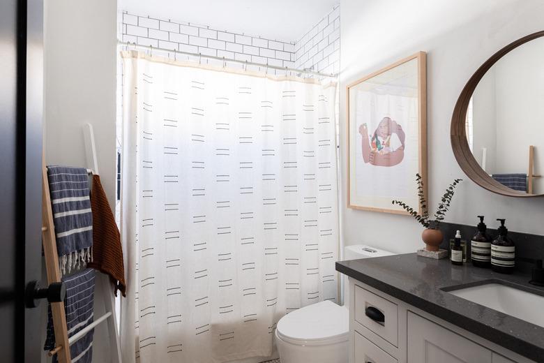 bathroom with shower, toilet, vanity cabinets and circular mirror