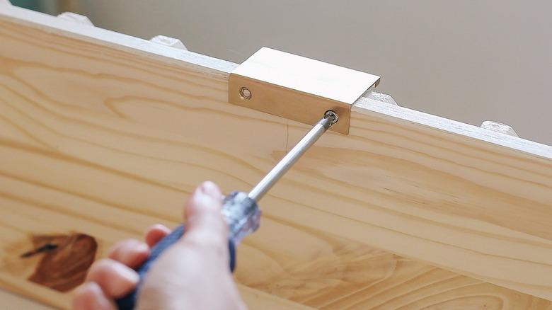 Hand using screwdriver on wood IKEA dresser