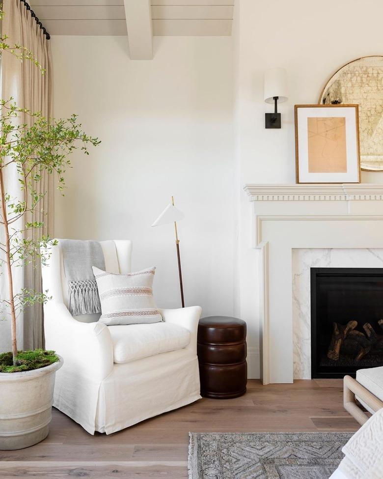 beige room with traditional fireplace and white armchair