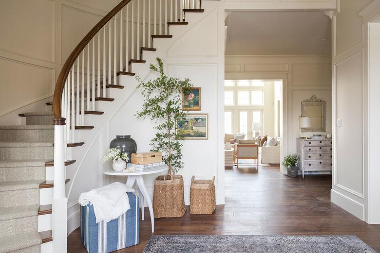 curved grand traditional staircase looking down over entryway table and potted tree