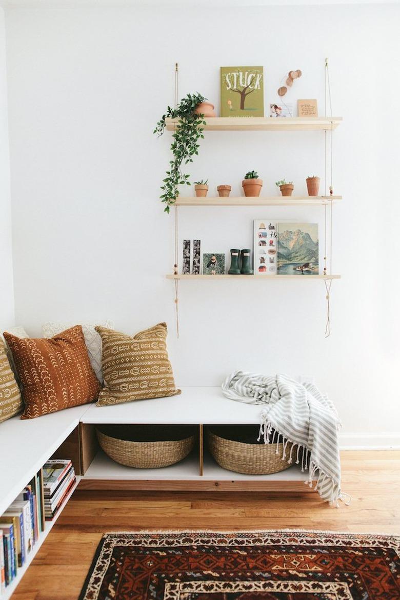 Living room storage ideas below corner seating and shelving on the wall