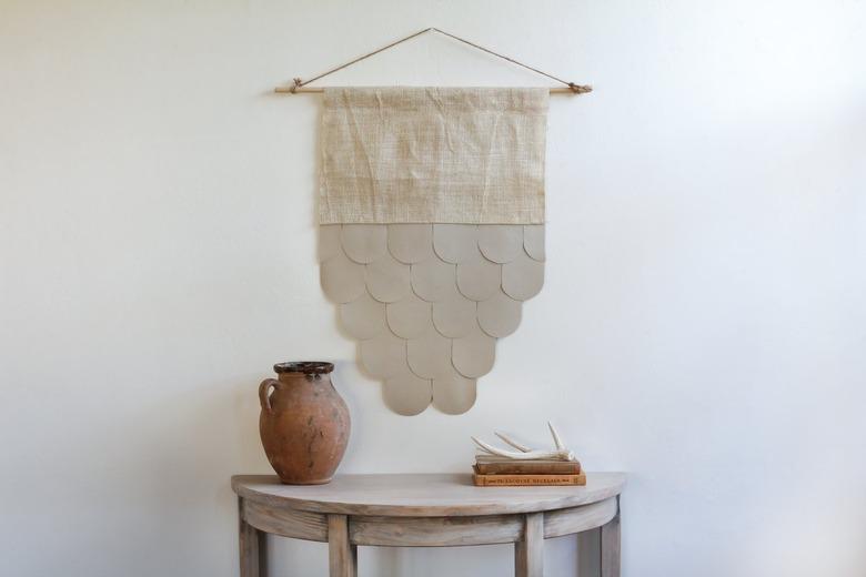 rustic decor with leather-burlap wall hanging over half-moon table with decorative vase