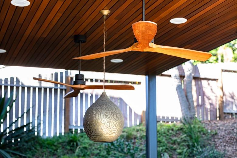 A wood ceiling with ceiling fans and a globe pendant light