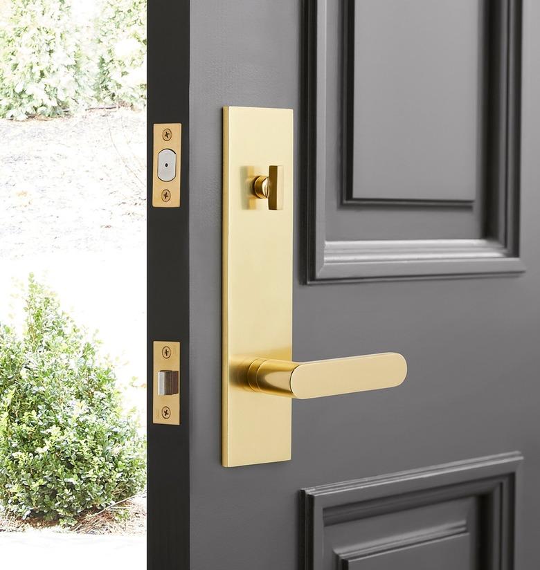 A black door with brass hardware opening to the outdoors