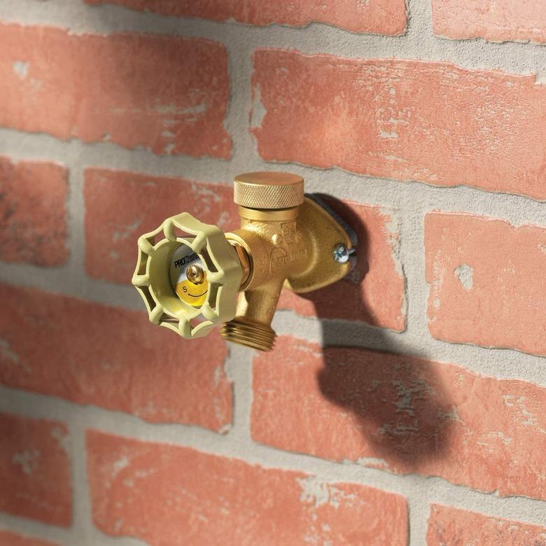 A brass frost-free faucet on a brick wall