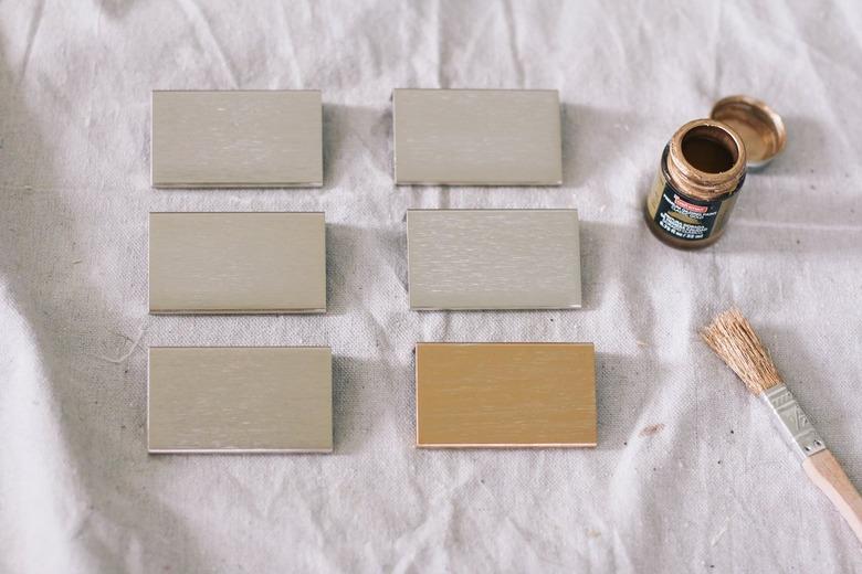 Six paint samples in pastel colors spread out on a white drop cloth