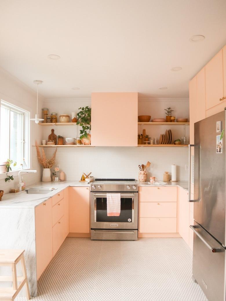 pink u-shaped kitchen with wood shelves