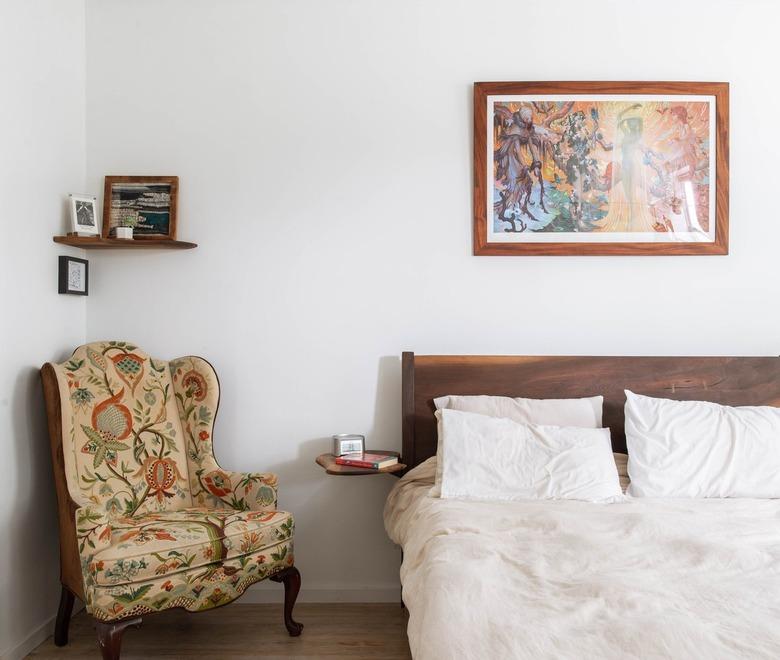 Bedroom with antique wingback chair and artwork over bed