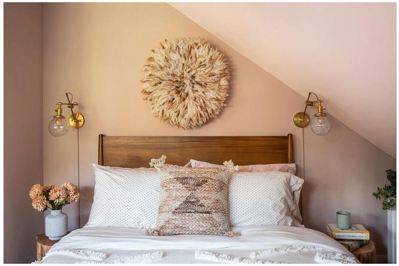 The head of a bed with two wall scones on either side.