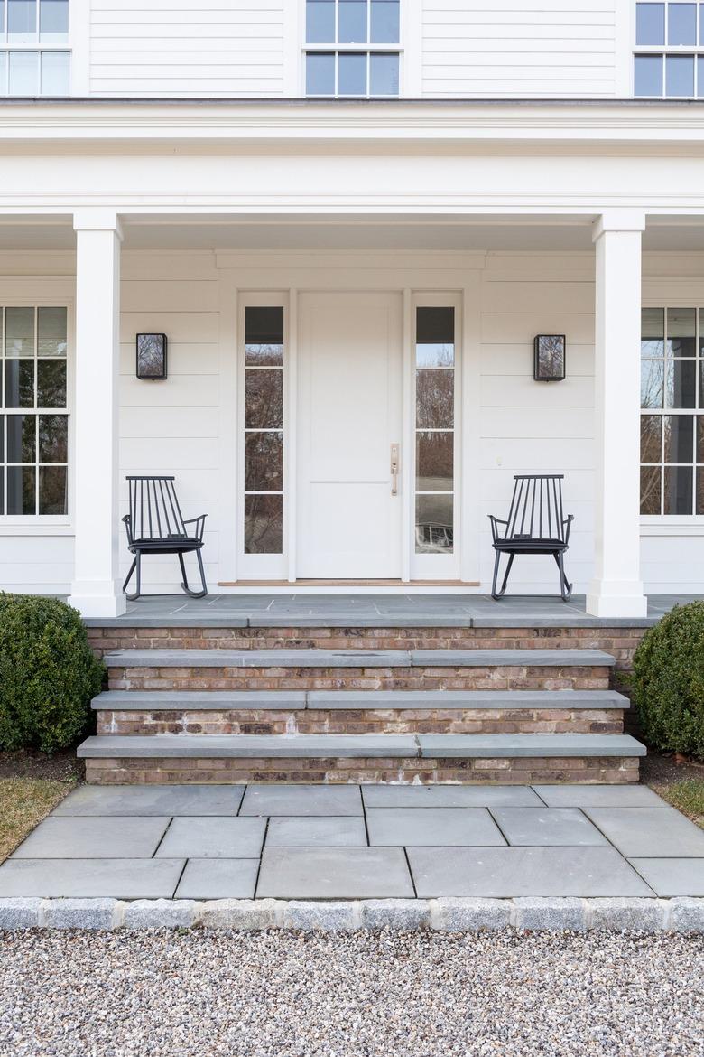 A front door and entryway with two rocking chairs.