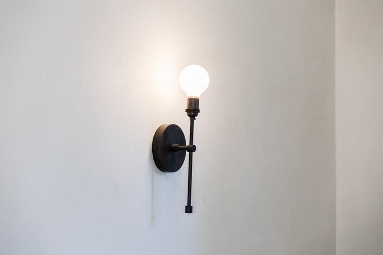 A globe light sconce on a white wall