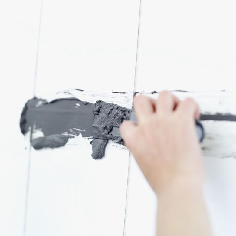 Hydraulic patch cement being applied by putty knife.