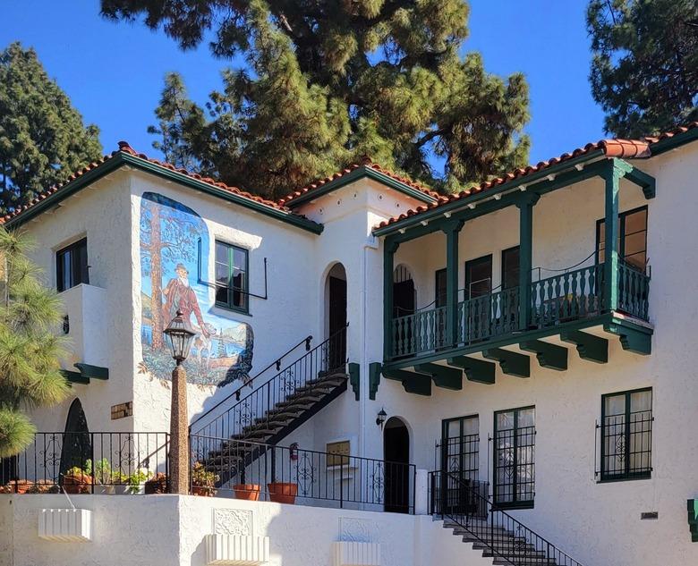 White Spanish style building with red tile roof and green balcony trim