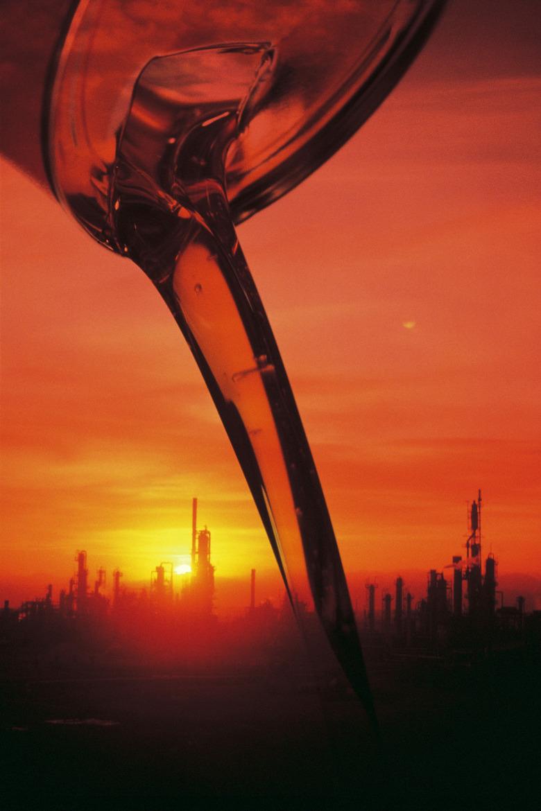 Oil pouring from a container , image of refinery background