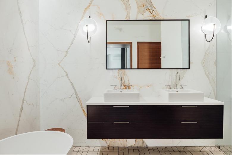 solid surface bathroom countertop with dark wood vanity and marble accent walls