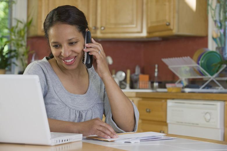 Hispanic woman working on a laptop and talking on a mobile phone