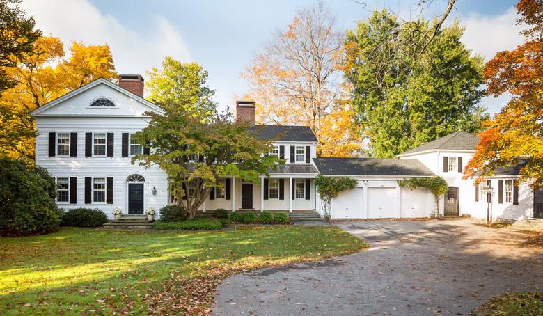 white garage door on colonial home surrounded by trees