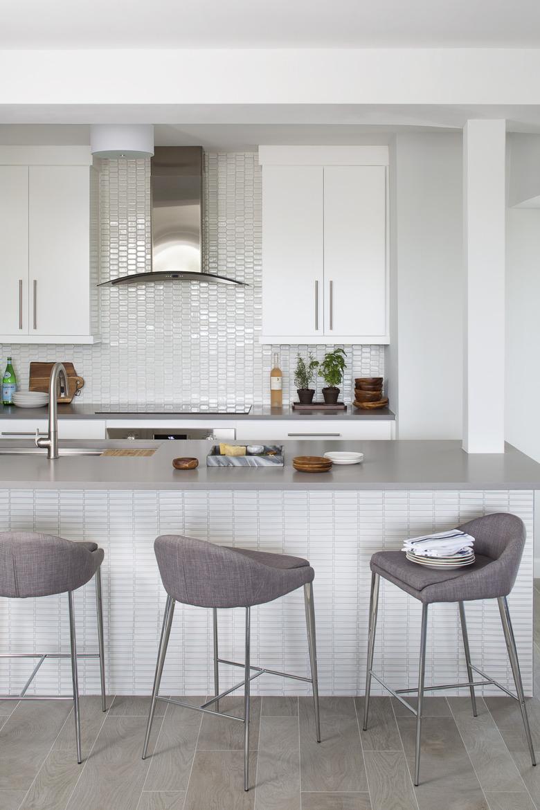 white kitchens with wood floors, gray island, and gray stools