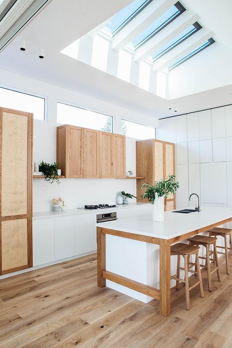 white kitchens with wood floors, vaulted ceiling with skylights, and wood cabinets