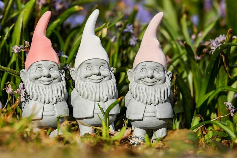 three gnome statues in a garden