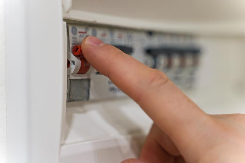 Male hand switching on fuse board.