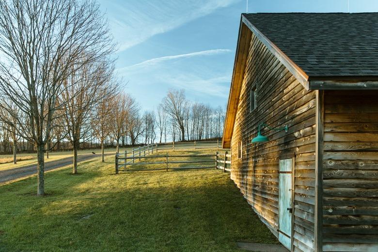 A wood cabin with a green lamp on a grass lawn with trees