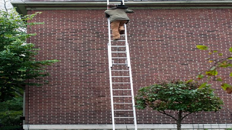 Carrying heavy slate roofing tiles up an extension ladder