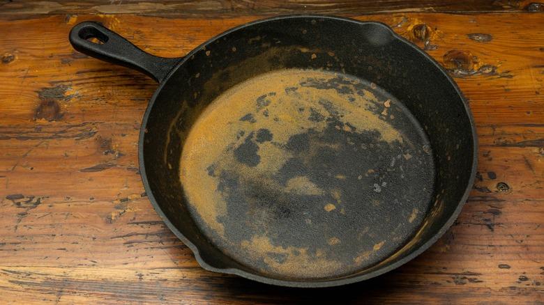 rusty cast iron skillet up close on a wooden table