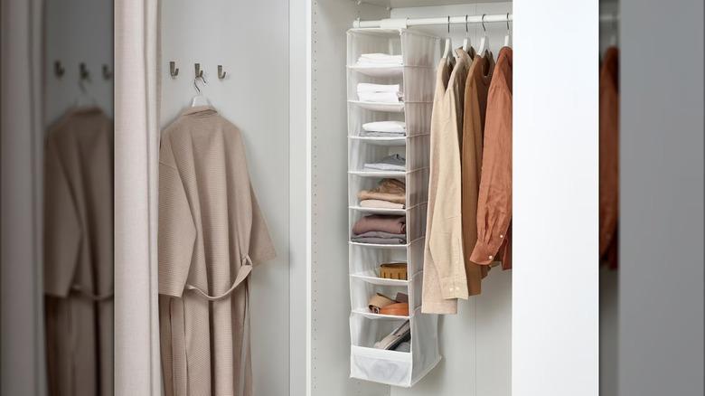 white wardrobe cabinet with a white IKEA SKUBB hanging fabric organizer with nine vertical compartments hanging from the closet rod