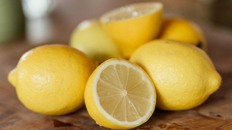 close-up of whole and halved lemons on wood surface