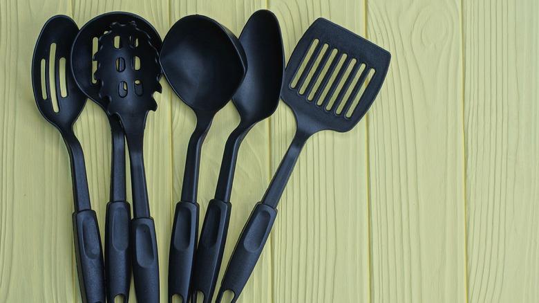 several black nylon kitchen utensils lined up in a row