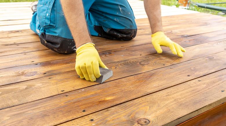 A person sanding down wood on a deck