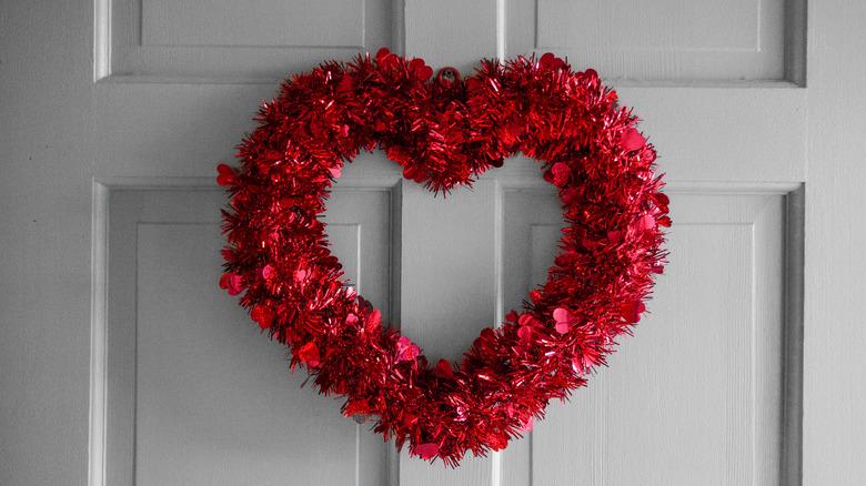 Red tinsel Valentine's Day heart-shaped wreath on a white door