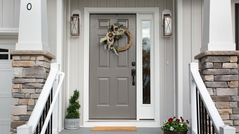 Close up of a dark gray door against a light gray house.