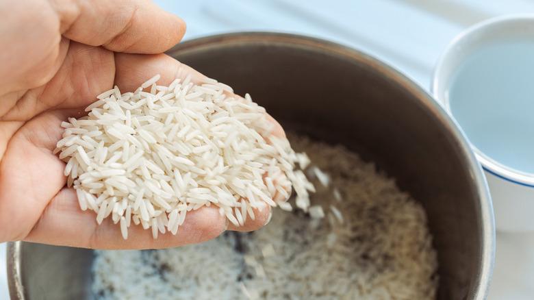 Grains of rice are being washed in a bowl.