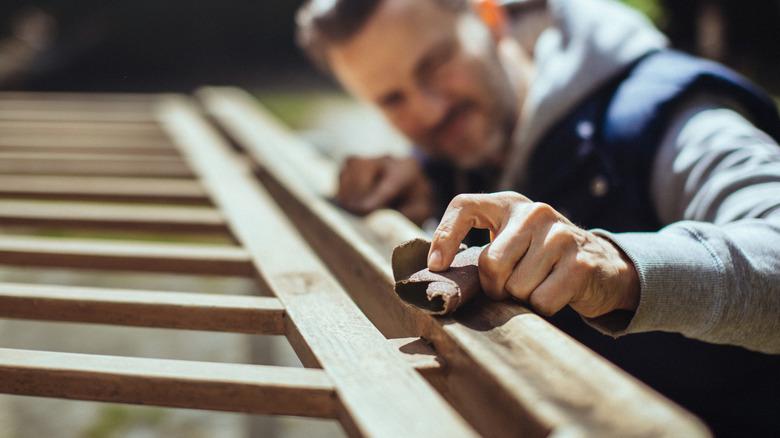 Man sanding wood outside.