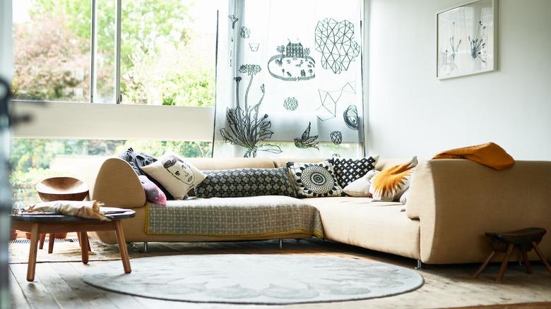 modern living room with sofa with short sleek legs, coffee table, decorative throw pillows, blankets, and wall decor