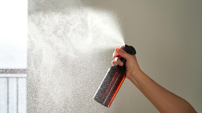 Spraying air freshener in a room