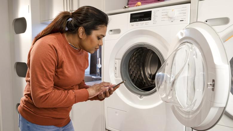 person repairing washer looking phone