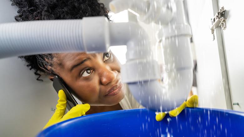 Woman on phone discussing leaking sink drain pipes