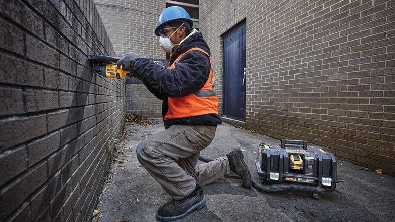 Man working with masonry and making use of DeWalt dust extractor